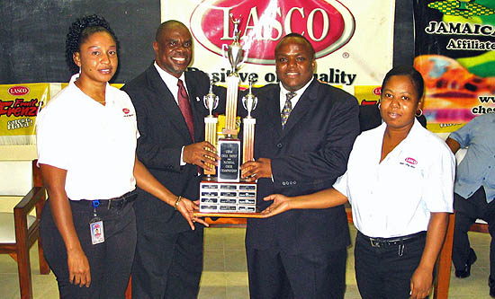 Duane Rowe receives his award from JCF President Ian Wilkinson while Alice Manhertz (left) and Swylen Davy (right) of LASCO Foods look on.