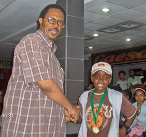 RJ Nelson wearing his medal after wining the under-10 title. Andrew Bowles of the T&T Chess Academy congratulates him.