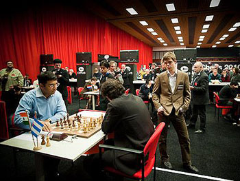 Anand squaring off with Dominguez with Nakamura and Carlsen watching. Photo by Fred Lucas.